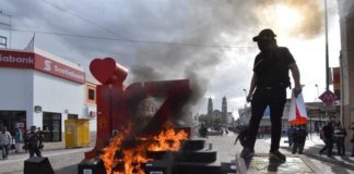 Provocan a policías con quema de monumento y grafiti a cara de Benito Juárez
