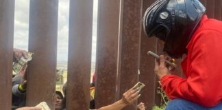 Repartidores de apps llegan a muro fronterizo para dar comida a migrantes